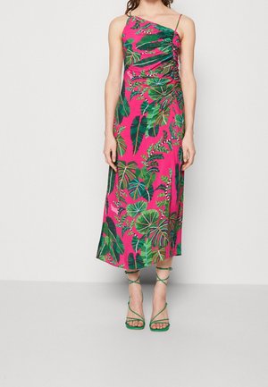 Vaaleanpunainen mekko, jossa on vihreitä trooppisia lehtikuvioita, yhdellä olalla ja kerrostetulla yksityiskohdalla. Vihreät hihna-sandaalit täydentävät asukokonaisuutta.