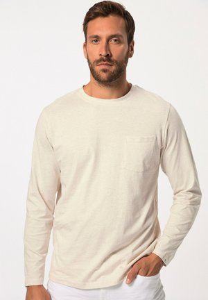 Ein hellbeiges Langarmhemd mit rundem Ausschnitt und einer Brusttasche. Der Stoff hat ein weiches, strukturiertes Aussehen und einen lässigen Schnitt.