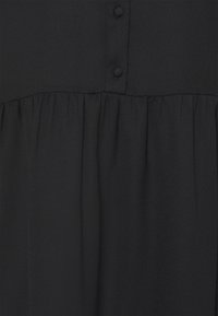 Czarna tkanina sukienki o teksturowanym wyglądzie, z guzikami na bodice i marszczoną, plisowaną częścią spódnicy.