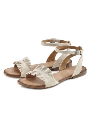 Beige Wildledersandalen mit rüschigem Vorderriemen, Knöchelriemen mit Schnalle und flacher Holzsohle. Offene Zehenform für Atmungsaktivität.