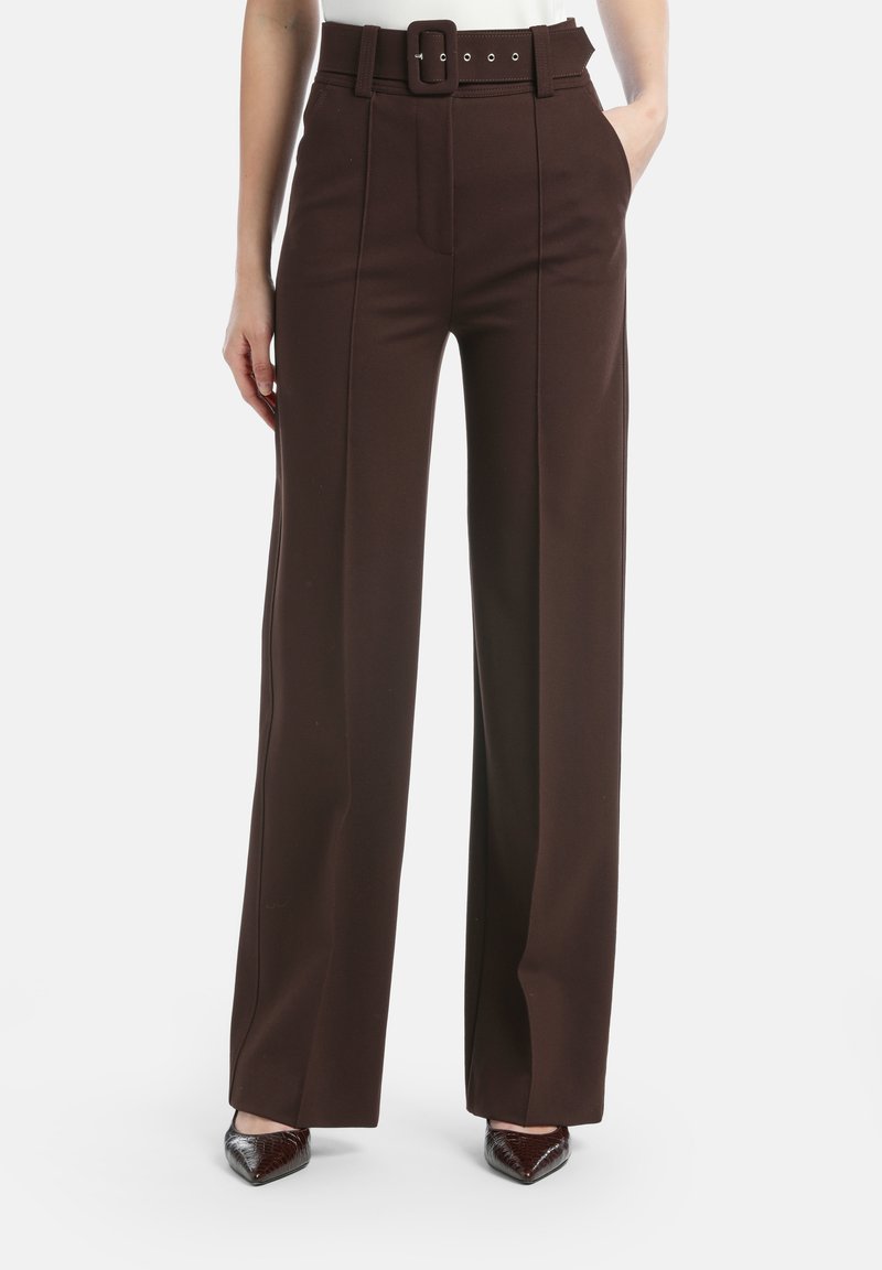 Brūni, plati bikses no bieza auduma ar augsto vidukļa dizainu, jostu ar taisnstūra sprādzi un sānu kabatām.