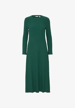 Vestido verde de manga larga con una tela texturizada. Tiene un escote redondo y una silueta fluida, con un dobladillo ondulado.