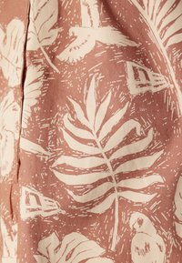 Cotton fabric featuring a blush pink background with white botanical and bird patterns, including leaves and stylized parrot illustrations.