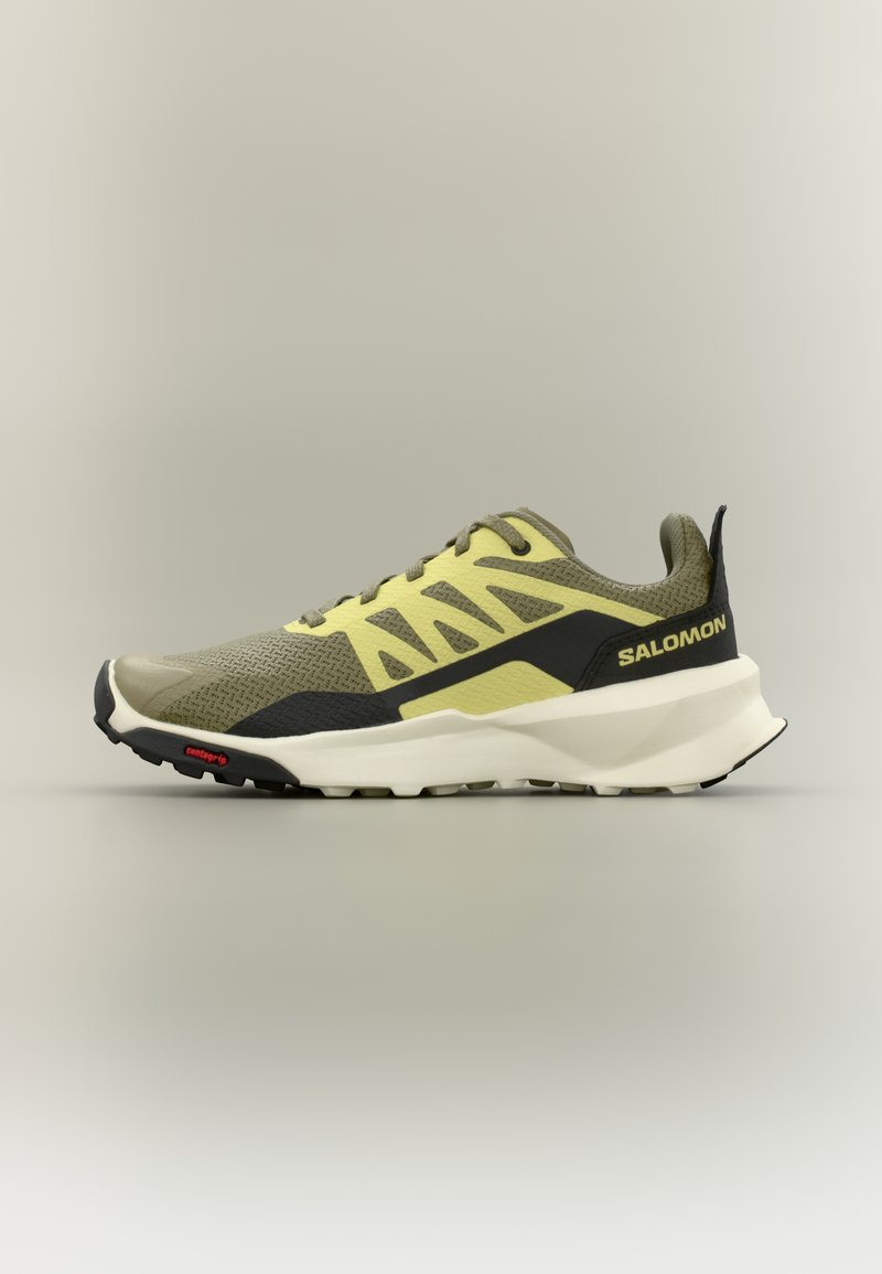 Αθλητικό παπούτσι για τρέξιμο σε μονοπάτια σε ανοιχτό ελαιώδες πράσινο και κίτρινο, με λευκή σόλα, μαύρες λεπτομέρειες, κορδόνια και λογότυπο Salomon στη φτέρνα.