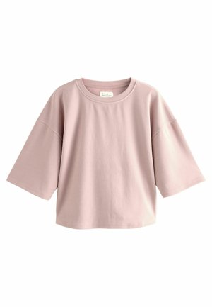 T-shirt di cotone rosa chiaro con scollatura rotonda e maniche corte e larghe. Texture liscia, vestibilità rilassata, con un'etichetta visibile sul collo.