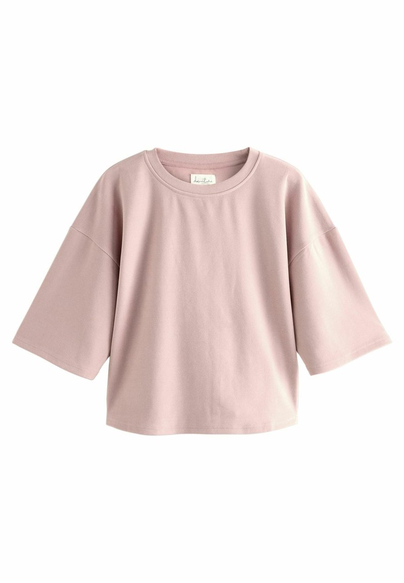 Lichtroze katoenen T-shirt met een ronde hals en korte, brede mouwen. Soepele textuur, ontspannen pasvorm, met een label zichtbaar bij de hals.