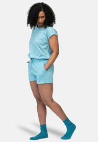 lichtblauwe katoenen t-shirt met korte mouwen en kleine geborduurde details, gecombineerd met bijpassende shorts en gezellige, geribbelde blauwe sokken.