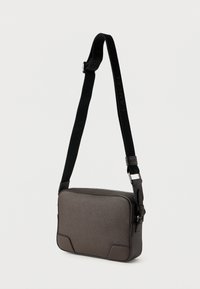 Ορθογώνια τσαντάκι ώμου σε σκούρο γκρι με υφή στην επιφάνεια, μαύρο ρυθμιζόμενο λουρί ώμου με τη σήμανση "LANCEL" και κλείσιμο με φερμουάρ.