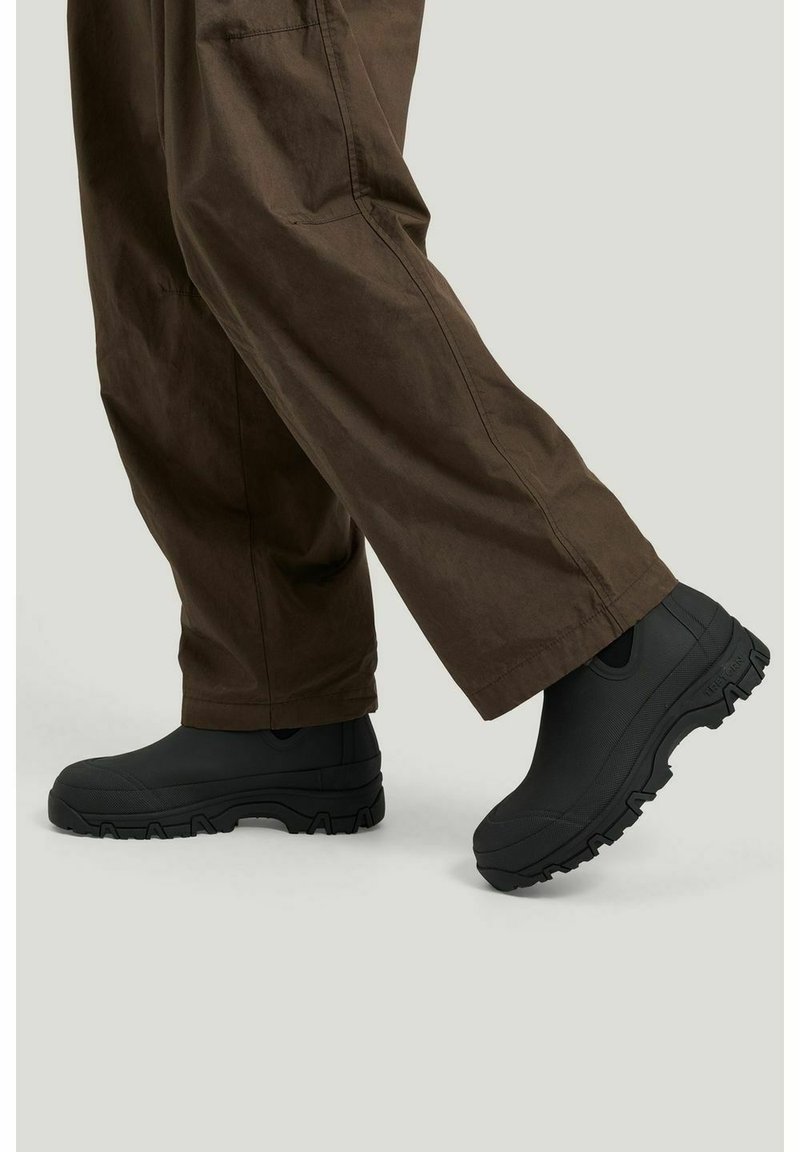 Sorte vandtætte sko med en tekstureret overflade og en tyk gummiydersål, der har sideudskæringer for åndbarhed og et sporty design.