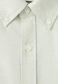 Lys beige skjortekrave med tre synlige hvide knapper og flot syning på struktureret stof.