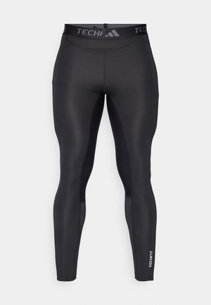Black athletic leggings made from smooth, stretchy material. Features a high waistband with "TECHFIT" logo and tapered legs with a sleek design.