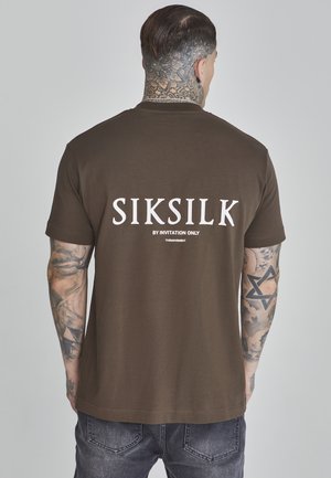 Pruun puuvillane T-särk, mille taga on suur valge "SIKSILK" logo. Lühikesed varrukad, tavaline lõige ja sile tekstuur.