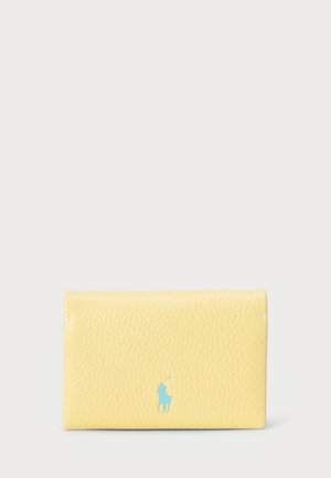 Gelbe Ledergeldbörse mit strukturiertem Finish. Verfügt über ein blaues Logo. Kompakte rechteckige Form mit sicherem Verschluss.