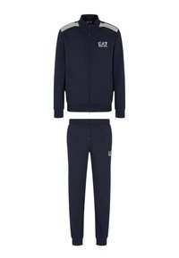 Marinblå träningsdräkt i mjukt tyg. Består av en zip-up jacka med ståkrage och randiga detaljer, tillsammans med matchande joggers.
