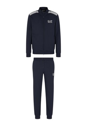 Chándal azul marino hecho de tejido suave. Cuenta con una chaqueta con cremallera y cuello alto, y acentos a rayas, acompañada de pantalones jogger a juego.