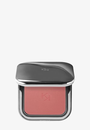 Compact blush with a shiny silver lid, featuring a soft pink hue inside. Textured surface with engraved logo. Square shape with rounded edges.