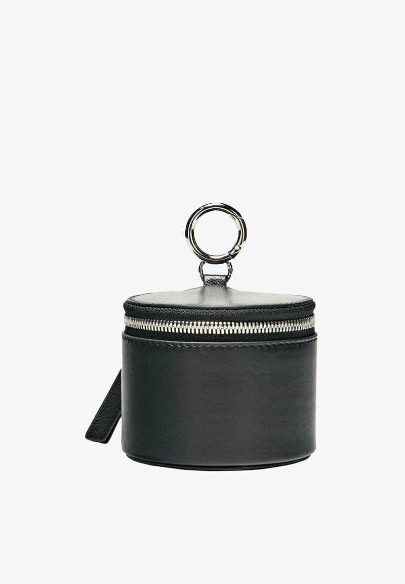 Pochette cylindrique en cuir noir avec fermeture éclair argentée et grande bague de clé argentée accrochée sur le dessus, sur fond blanc.