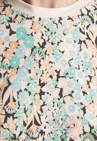 Tissu à motif floral avec des fleurs pastel bleu, vert et pêche sur un fond noir ; matériau doux avec une texture légère.