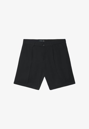 Schwarze, maßgeschneiderte Shorts mit vorderen Falten, Knopf- und Reißverschluss, Gürtelschlaufen und Seitentaschen, flach auf einem weißen Hintergrund ausgebreitet.