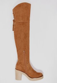 Botte en daim marron au-dessus du genou avec un talon bloc, une fermeture éclair latérale et des accents de ferrures décoratives. Texture lisse et design sur mesure.