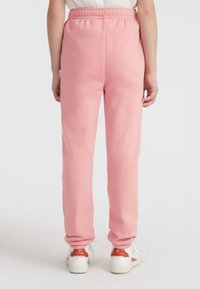 Roze sweatpants met een elastische tailleband, taps toelopende pijpen en een zachte textuur. Versterkt met een klein logo-label aan de zijkant.