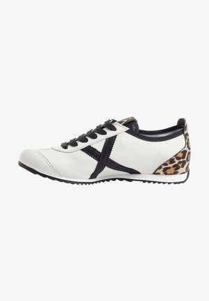 Valkoinen nahkakenkä mustilla nauhoilla ja yksityiskohdilla. Sisältää leopardikuvioisen paneelin kantapäässä ja teksturoidun kumipohjan.