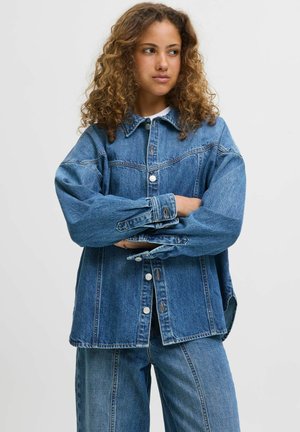 Džínová bunda, světle modrá, oversized střih, zapínání na knoflíky, dvě náprsní kapsy, viditelné švy, texturovaná látka, spárovaná s odpovídajícími džíny.