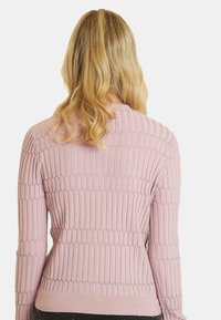 Jasnoróżowy sweter z prążkowanej tkaniny w fale, z długimi rękawami i dopasowanym krojem. Miękka tekstura i okrągły dekolt.
