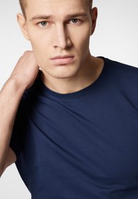 Granatowa koszulka z okrągłym dekoltem, wykonana z gładkiej bawełny, z krótkimi rękawami i dopasowanym krojem, z minimalnymi widocznymi szwami.