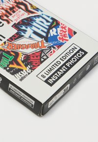 Mustvalge kast, millel on erksad kleebised, tekstiga "8 PIIRATUD VERSIOONI INSTANTFOTODEGA." Erinevad graafilised kujundid ja mustrid on nähtavad.