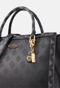 Černá kožená kabelka s embosovaným vzorem loga, zlatými kovovými akcenty, dvojitými uchy a dekorativním klíčenkou se značkovou visačkou.