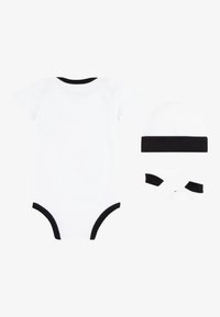 Body alb cu mâneci scurte și margini negre, însoțit de o pălărie și șosete asortate, toate dintr-un material moale cu textură netedă.