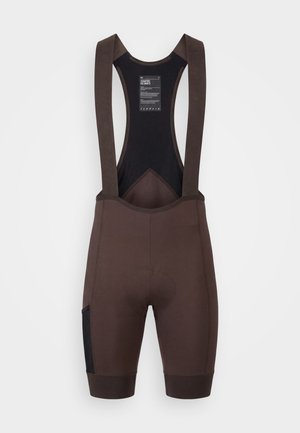 Pantaloncini da ciclismo marroni con spalline nere in mesh e area della sella imbottita, mostrati distesi su sfondo bianco.