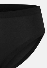 Schwarzer Baumwoll-Slip mit glatter Textur. Verfügt über einen breiten Gummibund und nahtlose Verarbeitung. Einfaches, minimalistisches Design.