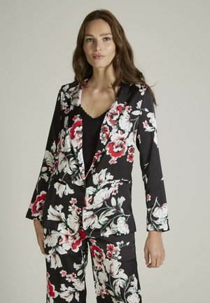 Blazer à imprimé floral noir, comportant des fleurs blanches et rouges. Design ajusté avec revers, fermeture à bouton et deux poches avant.