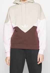 Hoodie med färgblockdesign i beige, rosa och brunt. Tillverkad av mjukt tyg med broderad logotyp på bröstet.