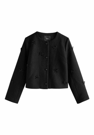 Black cropped jacket with long sleeves, textured fabric, adorned with small black bow accents, and front button closure.