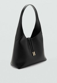 Sac à bandoulière en cuir noir avec une forme arrondie, présentant un accent doré sur la fermeture éclair et une texture lisse. Design minimaliste.