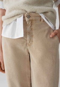 Pantaloni in corduroy beige con taglio dritto, dotati di chiusura a bottone, texture sottile e cuciture visibili lungo le cuciture.