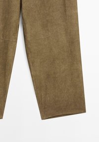 Pantaloni in corduroy verde oliva con una texture liscia, taglio dritto e due tasche frontali nascoste. L'orlo è leggermente svasato.