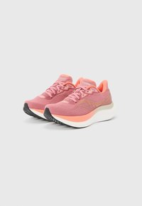 Ζευγάρι ροζ και κοραλί παπούτσια για τρέξιμο με λευκές χοντρές σόλες και μαύρο πέλμα, τοποθετημένα σε απλό ανοιχτό γκρι φόντο.