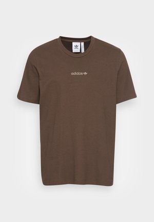 Ruskea Adidas T-paita, jossa on lyhyet hihat ja pieni beige Adidas-logo rintakehän keskellä yksiväristä taustaa vasten.