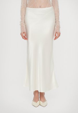 Witte satijnen rok met een strak ontwerp, vloeiende silhouet en subtiele glans. Gepaard met beige puntige ballerina's.