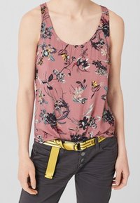 Top floreale senza maniche di un rosa chiaro con accenti neri, blu e gialli. Abbinato a pantaloni grigi e una cintura gialla con una fibbia a clip.