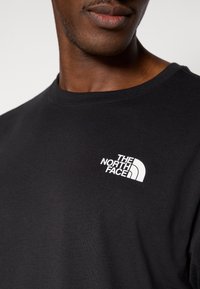 Μαύρο βαμβακερό T-shirt με κοντά μανίκια και στρογγυλή λαιμόκοψη. Διαθέτει λευκό λογότυπο στην αριστερή πλευρά του στήθους. Λείο ύφασμα.