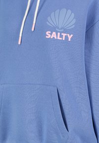 Blaue Kapuzenjacke aus weichem Stoff. Auf der Vorderseite mit pinkem "SALTY"-Text und Muschelgrafik versehen, weißen Kordeln und einer Fronttasche.