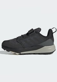 Zapatillas deportivas en negro y gris con parte superior de malla texturizada, tira en el talón y suela resistente diseñada para actividades al aire libre.