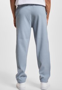 Lichtblauwe ribgebreide broek van zachte stof, met een elastische tailleband en zijzakken, gecombineerd met witte sneakers.