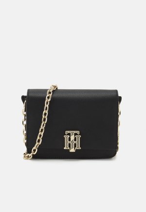Czarna skórzana torba na ramię z złotym łańcuszkiem i złotym przeplatającym się logo "TH" na przedniej klapie.