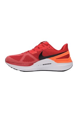 Sneakers atletici rossi con una tomaia in rete, logo Nike swoosh nero, accenti arancioni sul tallone e una intersuola in schiuma bianca.